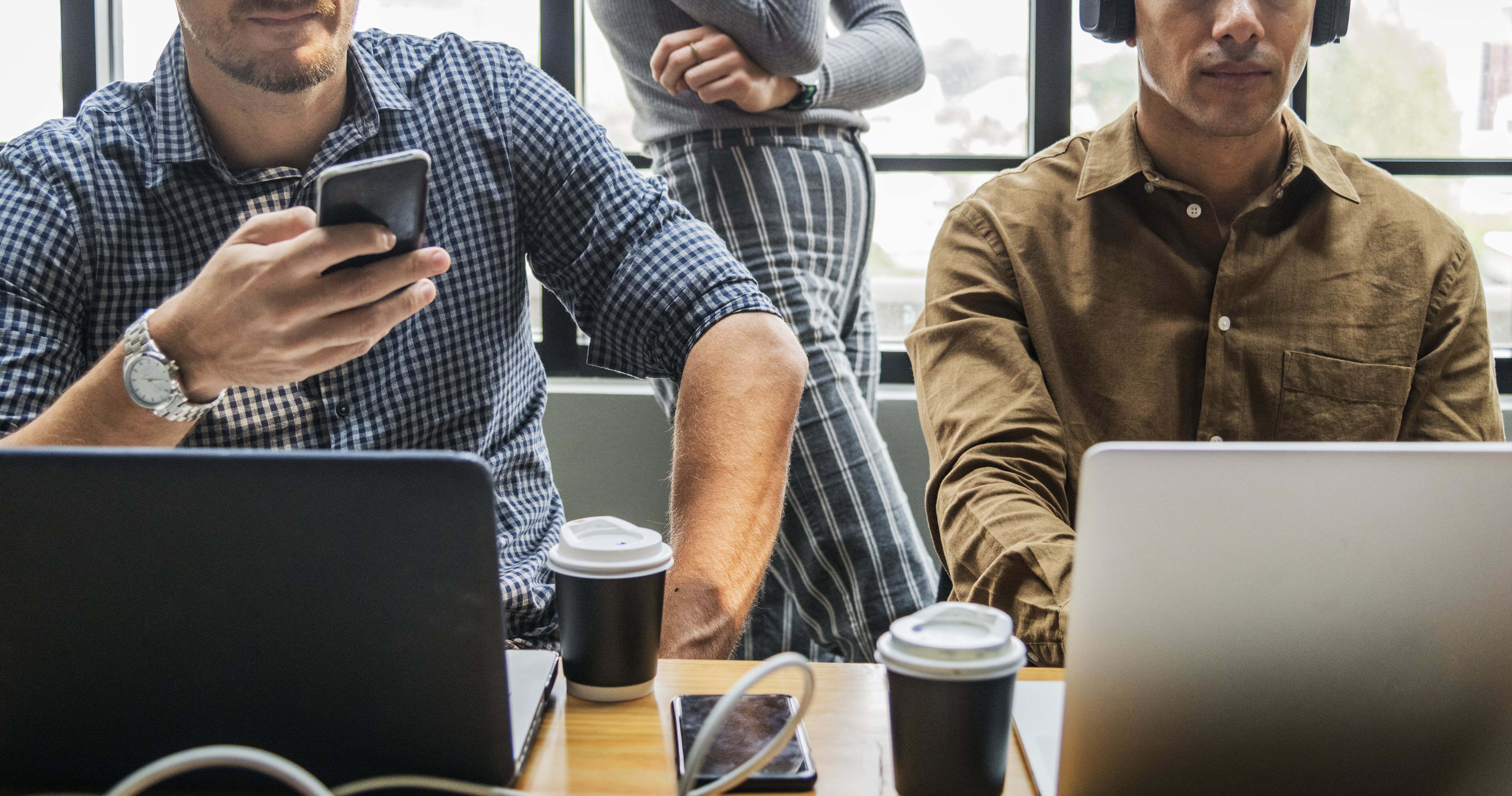 Collaborative team working with laptops and smartphones in a modern office, highlighting technology and communication in the workplace