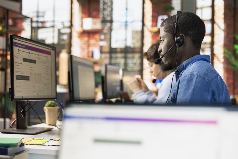Center center agents with headsets in front of digital service dashboards.